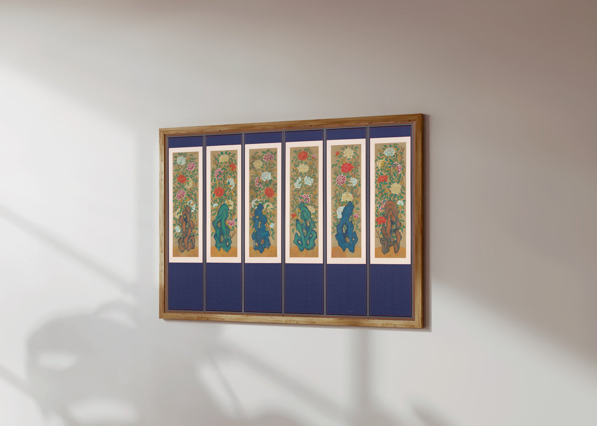 Framed art print of Peonies and Rocks by Korean minhwa painter (unidentified), in a light wood frame on a sunlit white wall, seen at a slight angle