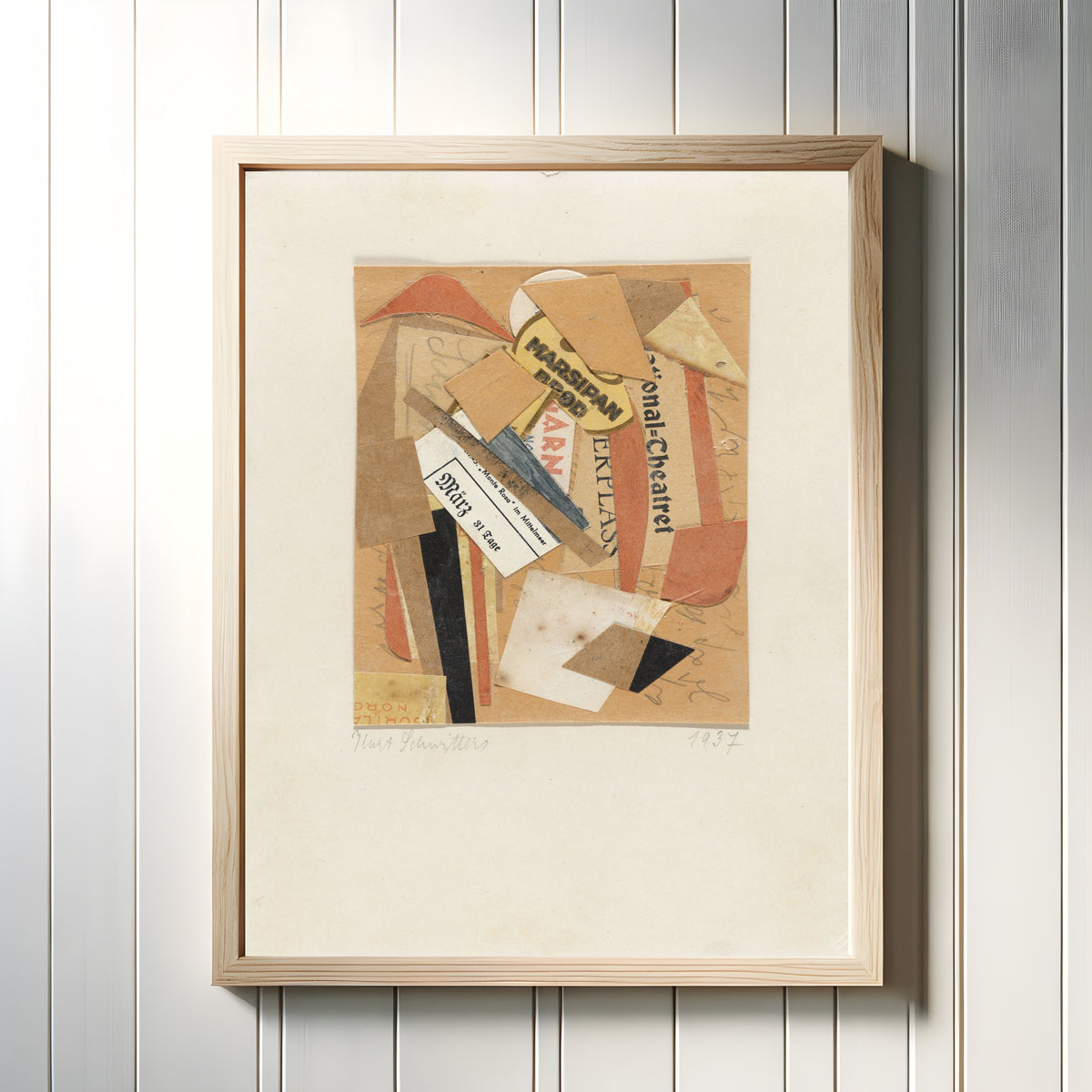 Framed art print of Collage by Kurt Schwitters, in a light wood frame on a white panelled wall