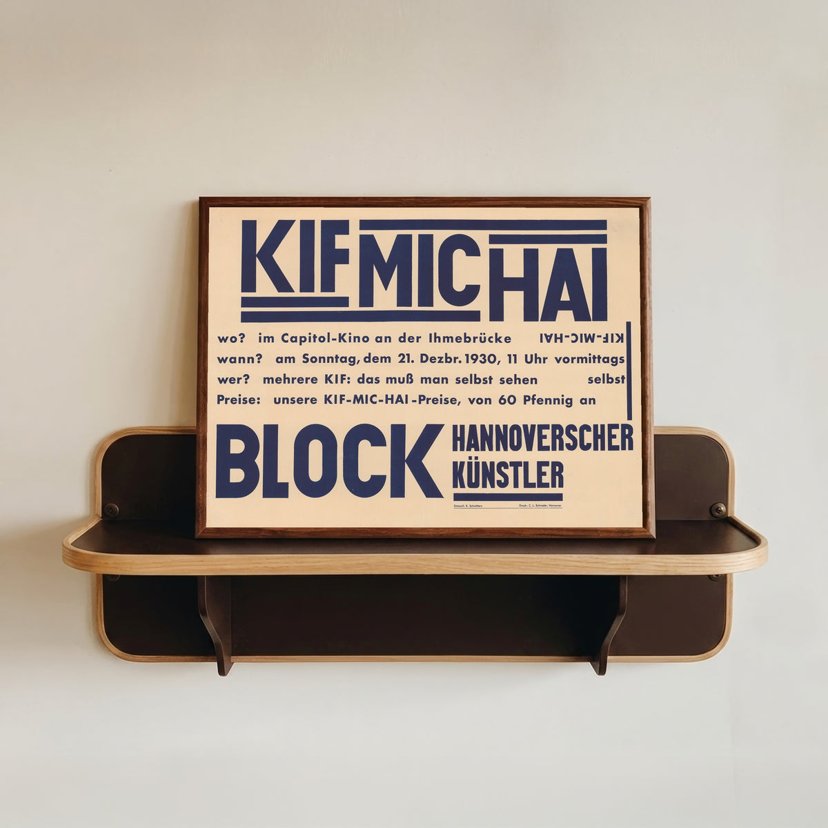 Framed art print of KIF MIC HAI, Block Hannoverscher Künstler by Kurt Schwitters, in a dark wood frame resting on a wall shelf