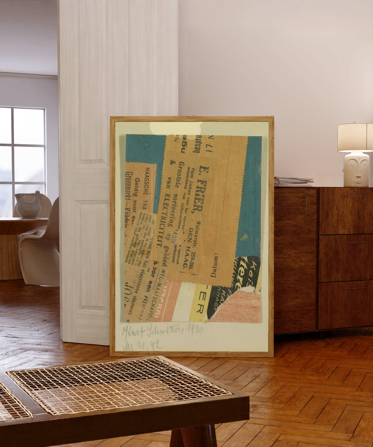 Framed art print of Merz 30, 42 by Kurt Schwitters, in a light wood frame leaning in a warm room with a parquet floor