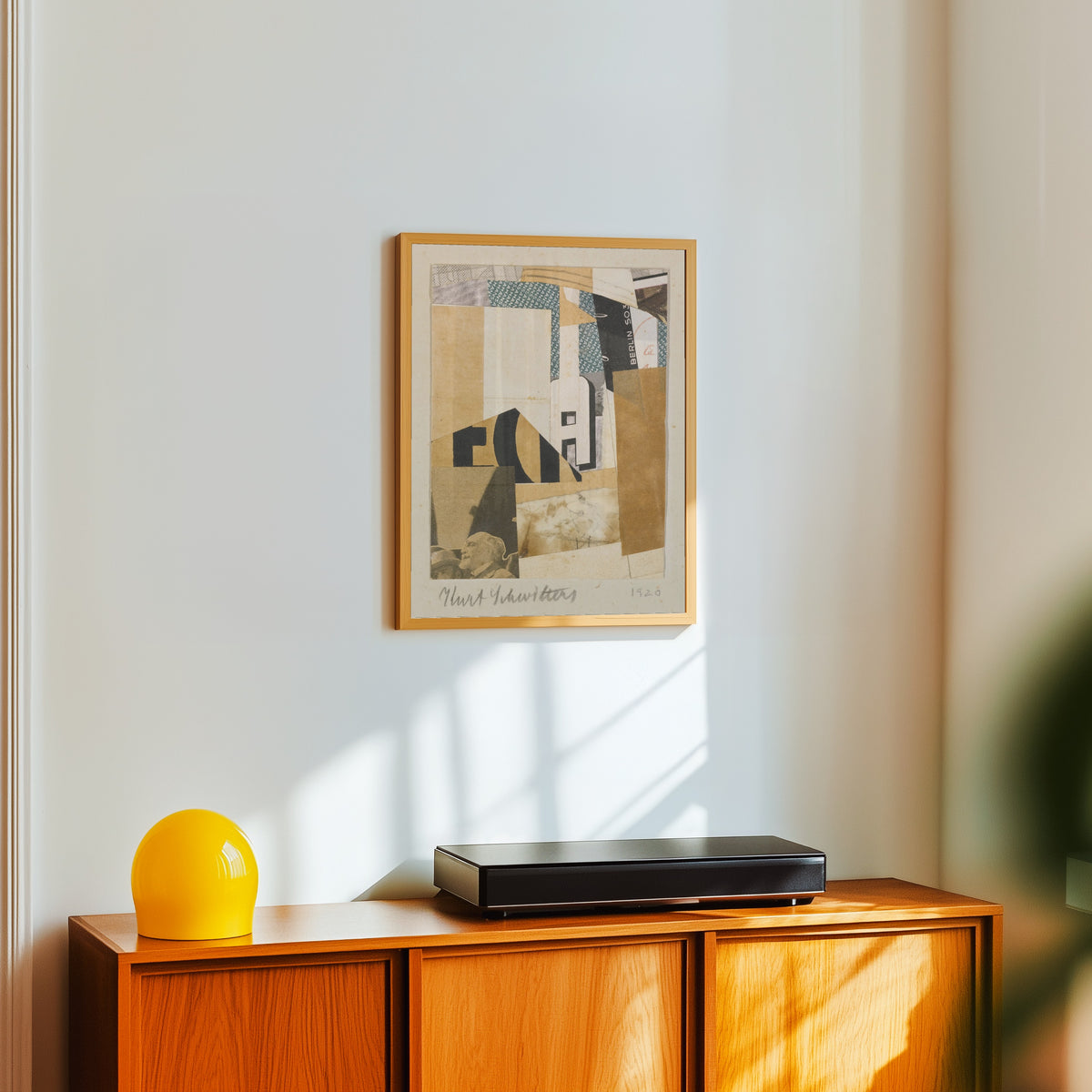 Framed art print of Ohne Titel, Berlin S 03 (Untitled, Berlin S 03) by Kurt Schwitters, in a light wood frame on a white wall above an orange sideboard