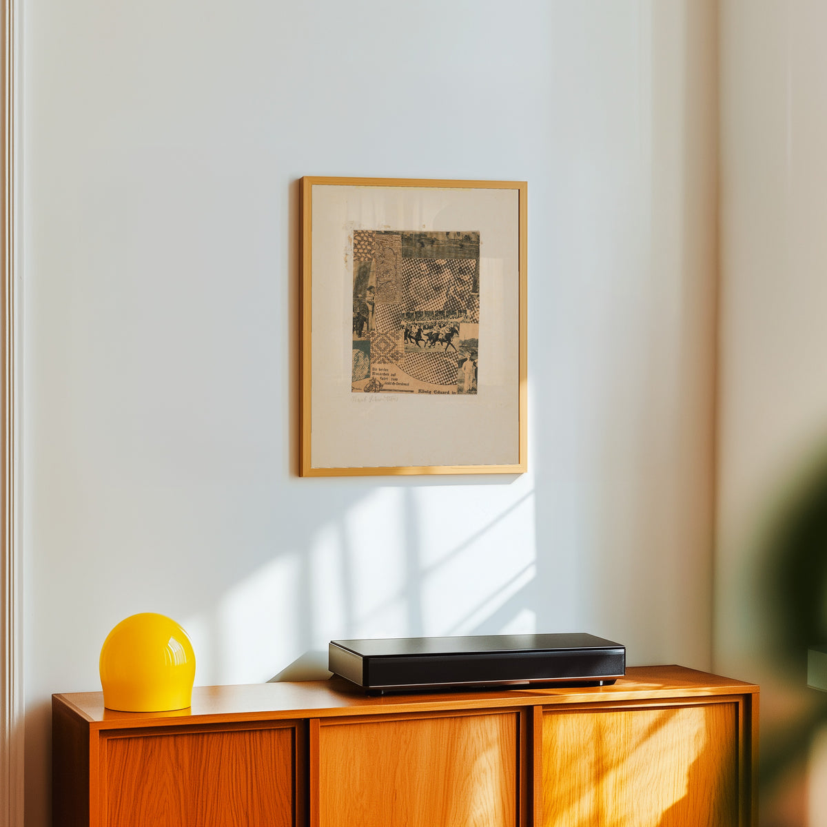 Framed art print of Ohne Titel (Köning Eduard in) by Kurt Schwitters, in a light wood frame on a white wall above an orange sideboard