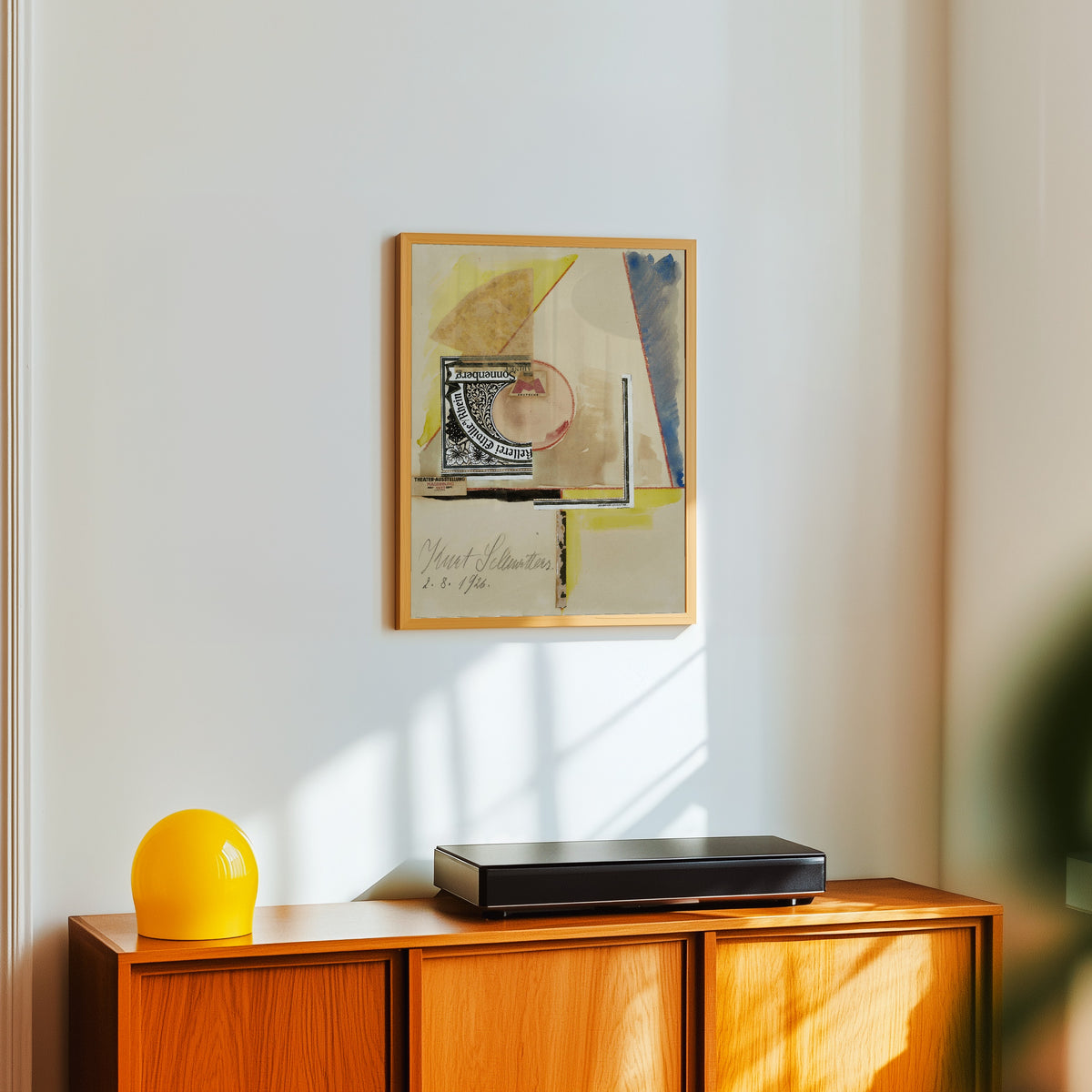 Framed art print of Ohne titel (Sonnenberg) by Kurt Schwitters, in a light wood frame on a white wall above an orange sideboard