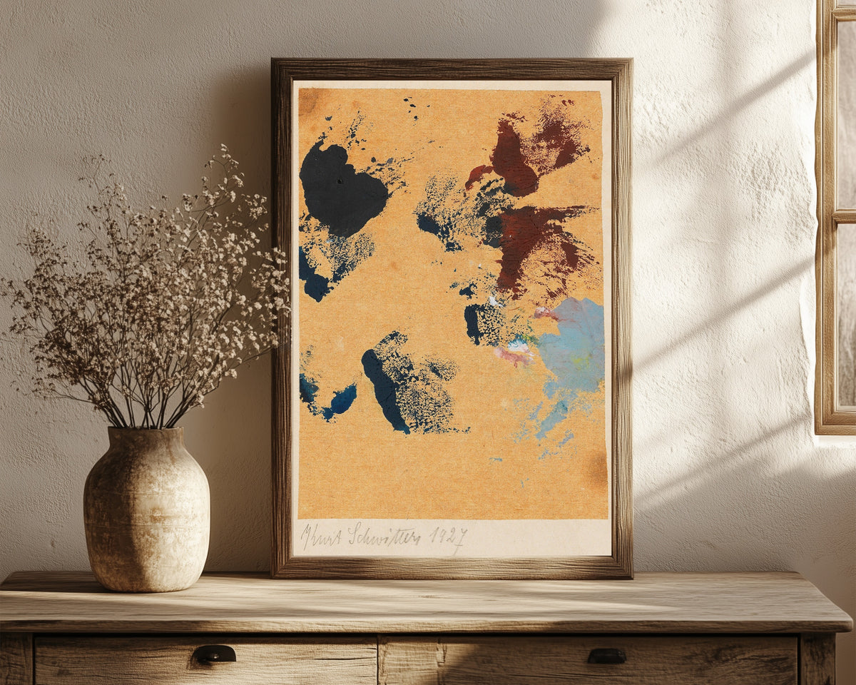 Framed art print of Ohne Titel (Spritzen Farbe) by Kurt Schwitters, in a dark wood frame leaning on a rustic console beside dried flowers