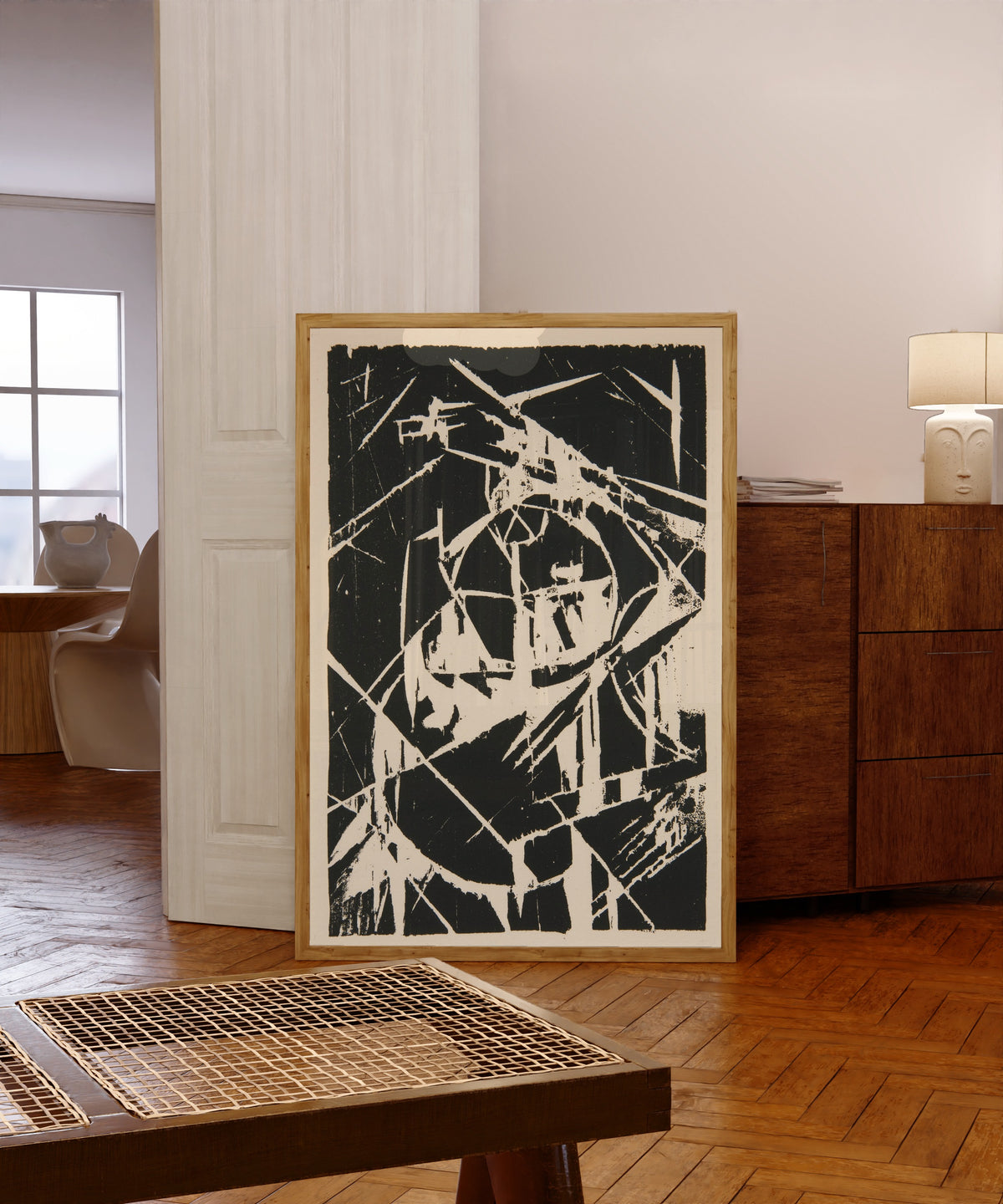 Framed art print of Plate XII from Das Kestnerbuch by Kurt Schwitters, in a light wood frame leaning in a warm room with a parquet floor