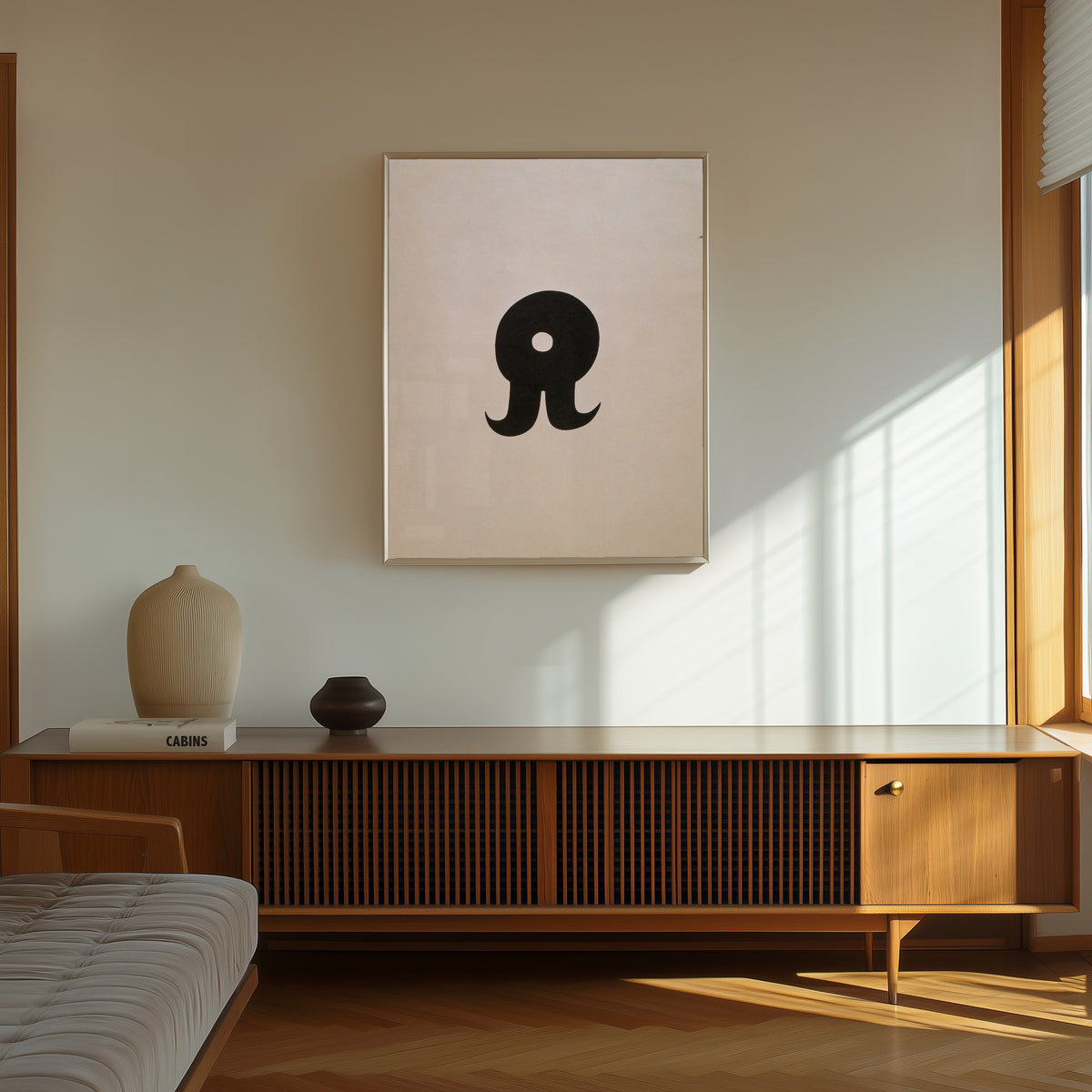 Framed art print of Schnurruhr by Kurt Schwitters, in a thin light frame on a sunlit wall above a wooden sideboard