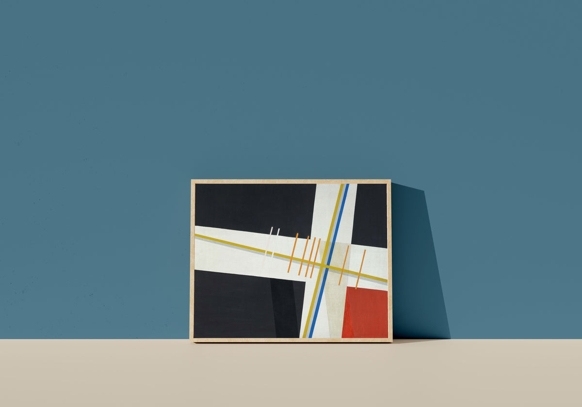 Framed art print of Am 3 by László Moholy-Nagy, in a light wood frame leaning on a blue wall