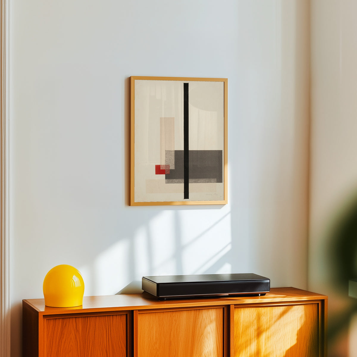 Framed art print of Composition (1923) by László Moholy-Nagy, in a light wood frame on a white wall above an orange sideboard