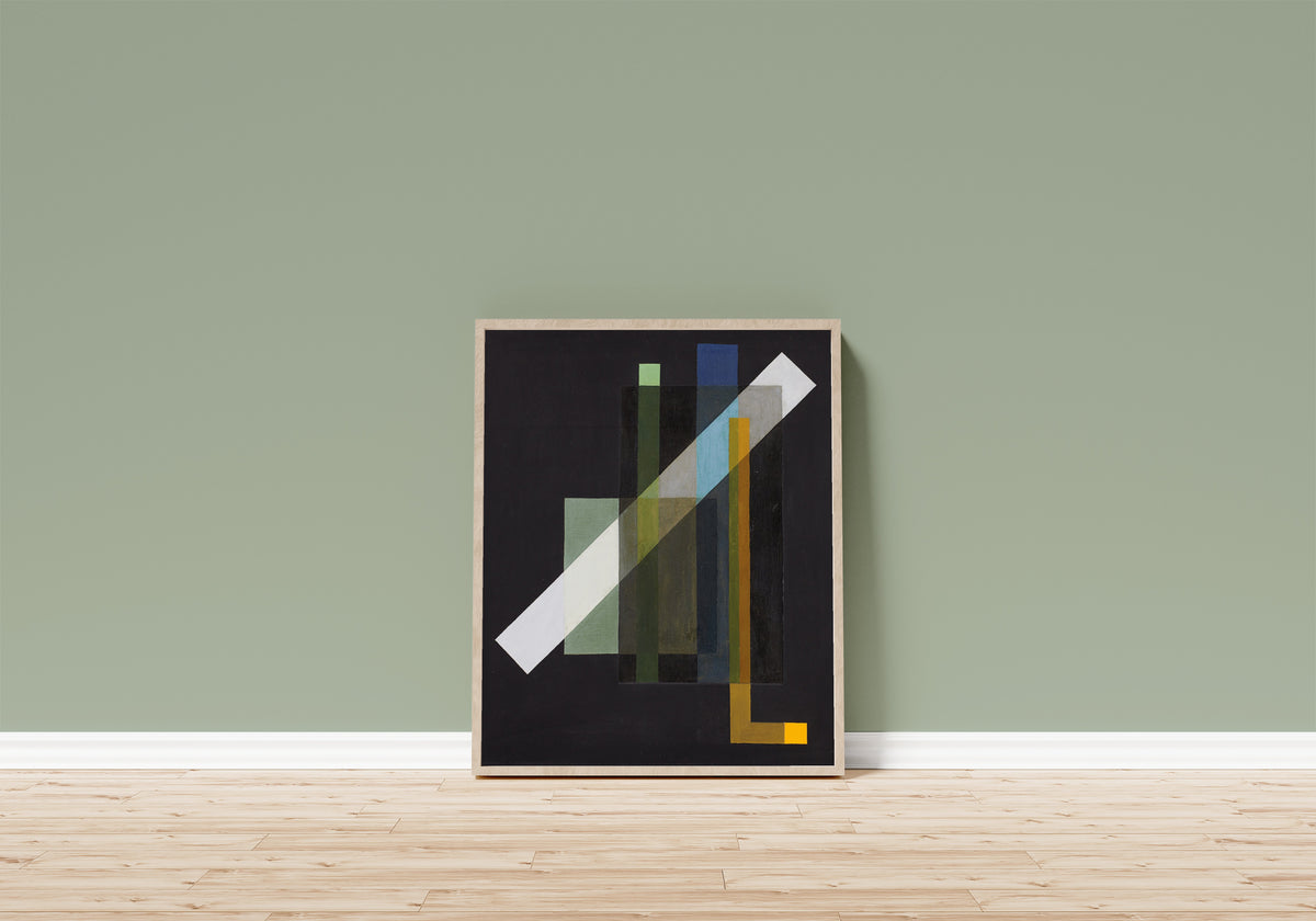 Framed art print of Construction (1924) by László Moholy-Nagy, in a light wood frame leaning on a sage green wall above a wooden floor