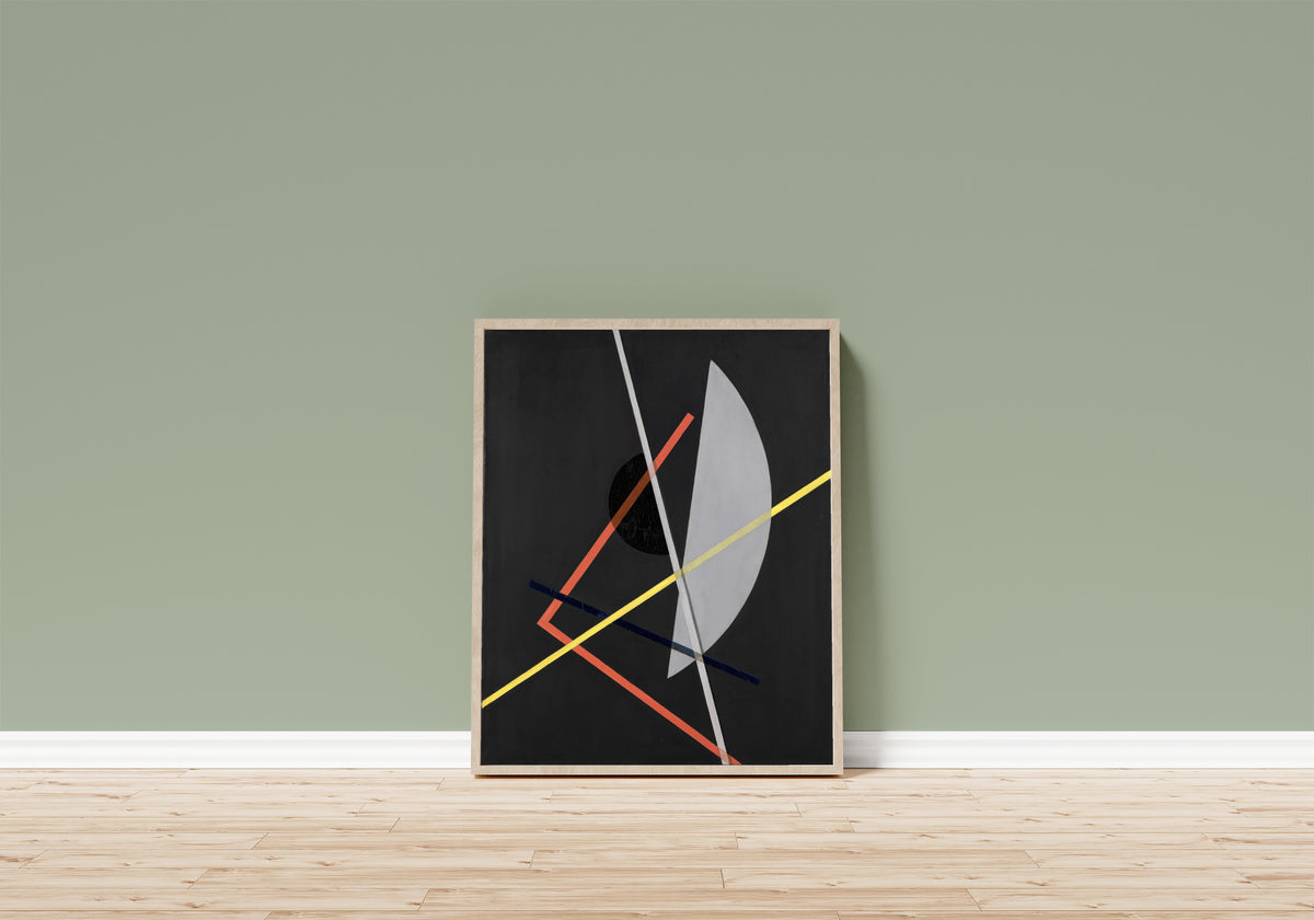 Framed art print of E IV (Konstruktion VII) by László Moholy-Nagy, in a light wood frame leaning on a sage green wall above a wooden floor