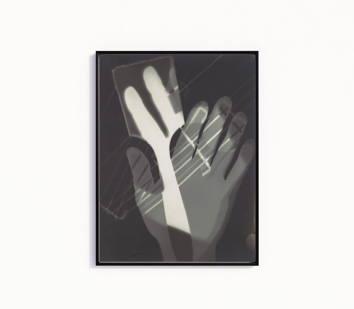 Framed art print of Fotogramm (1926) by László Moholy-Nagy, in a slim black frame on a plain white wall