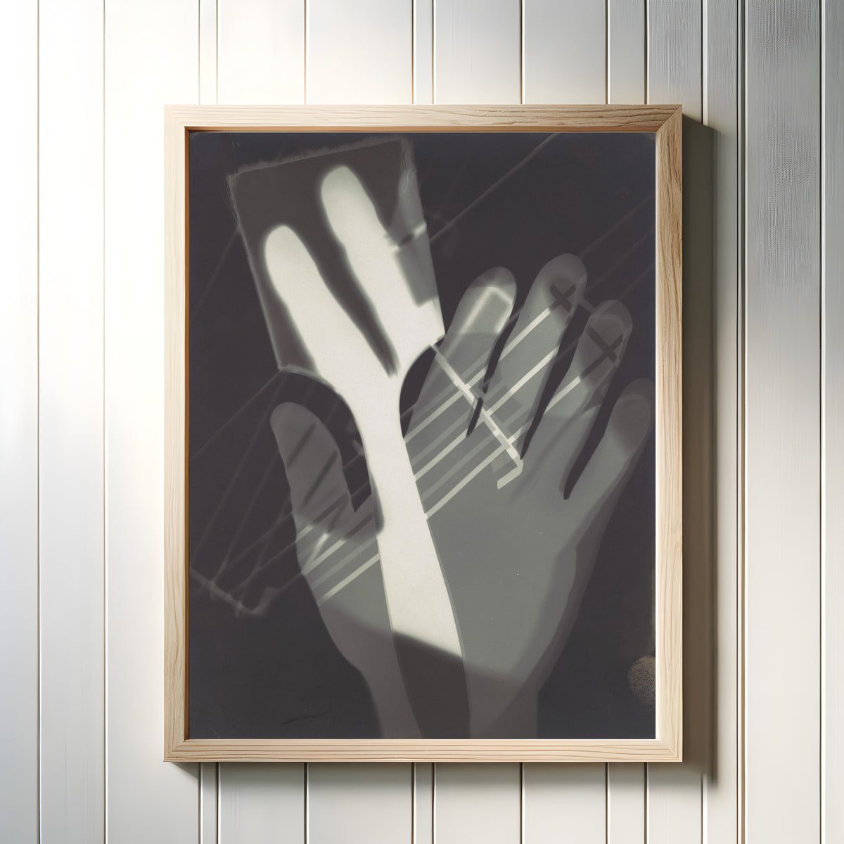 Framed art print of Fotogramm (1926) by László Moholy-Nagy, in a light wood frame on a white panelled wall