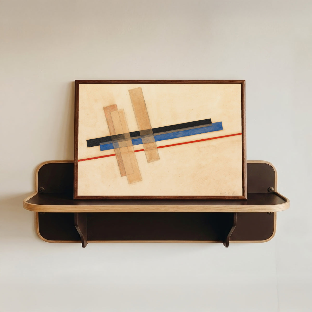 Framed art print of Komposition by László Moholy-Nagy, in a dark wood frame resting on a wall shelf