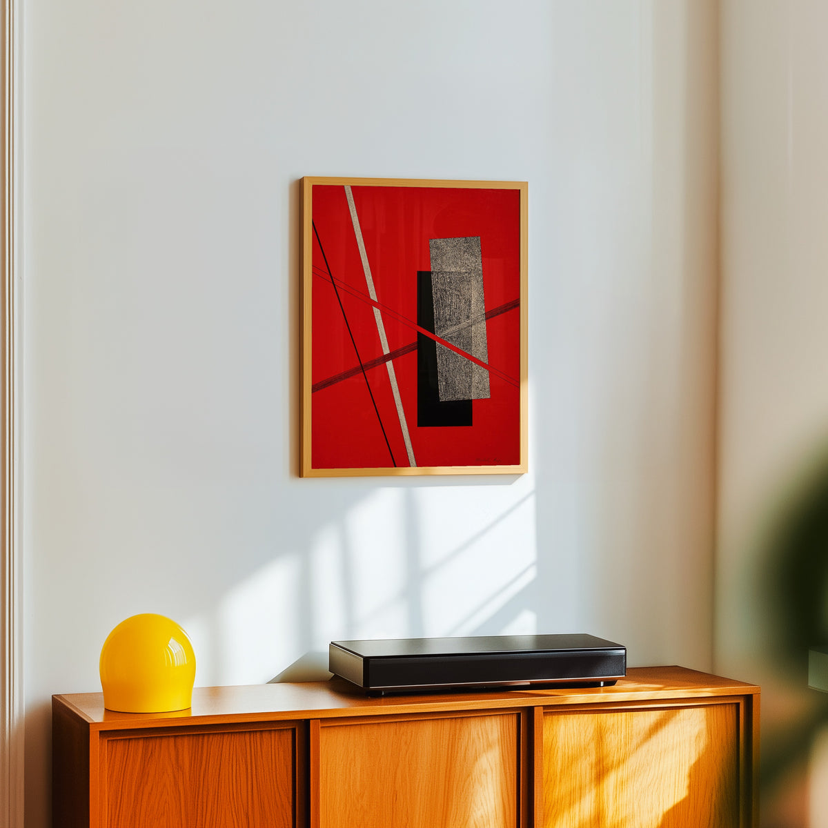 Framed art print of Konstruktion IV by László Moholy-Nagy, in a light wood frame on a white wall above an orange sideboard