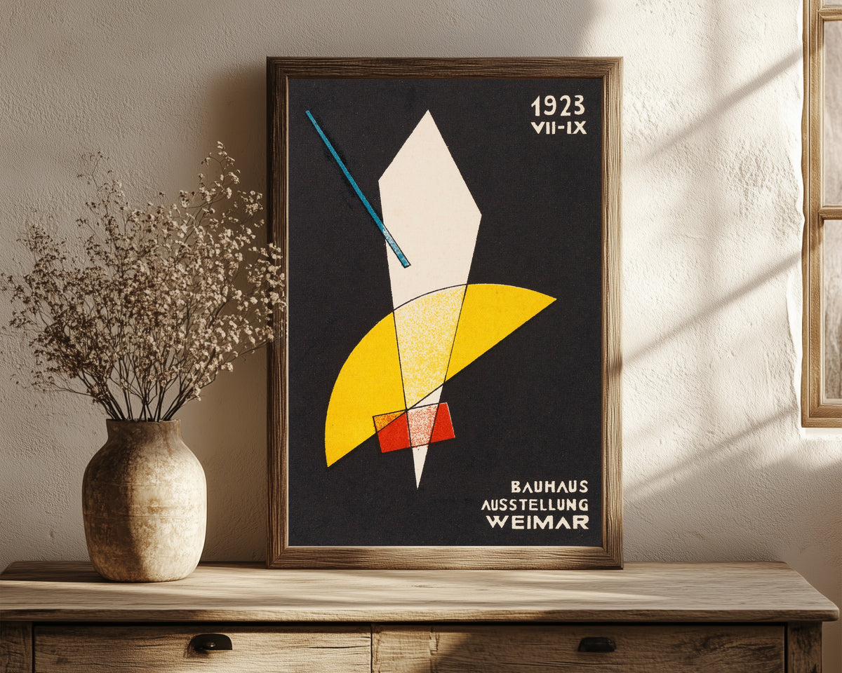 Framed art print of Weimar Bauhaus Postkarte Nr 7 by László Moholy-Nagy, in a dark wood frame leaning on a rustic console beside dried flowers