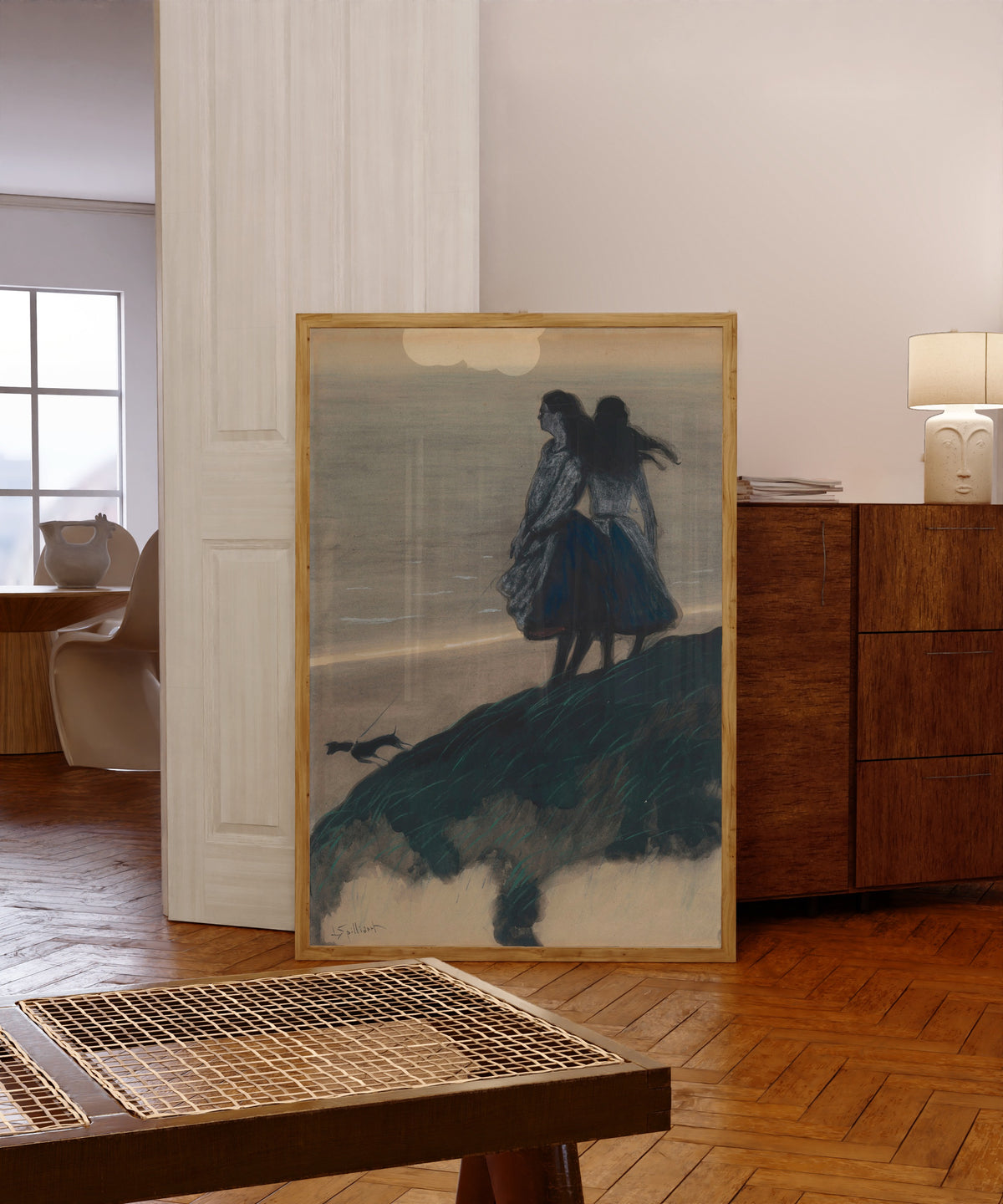 Framed art print of Girls on a Dune by Léon Spilliaert, in a light wood frame leaning in a warm room with a parquet floor