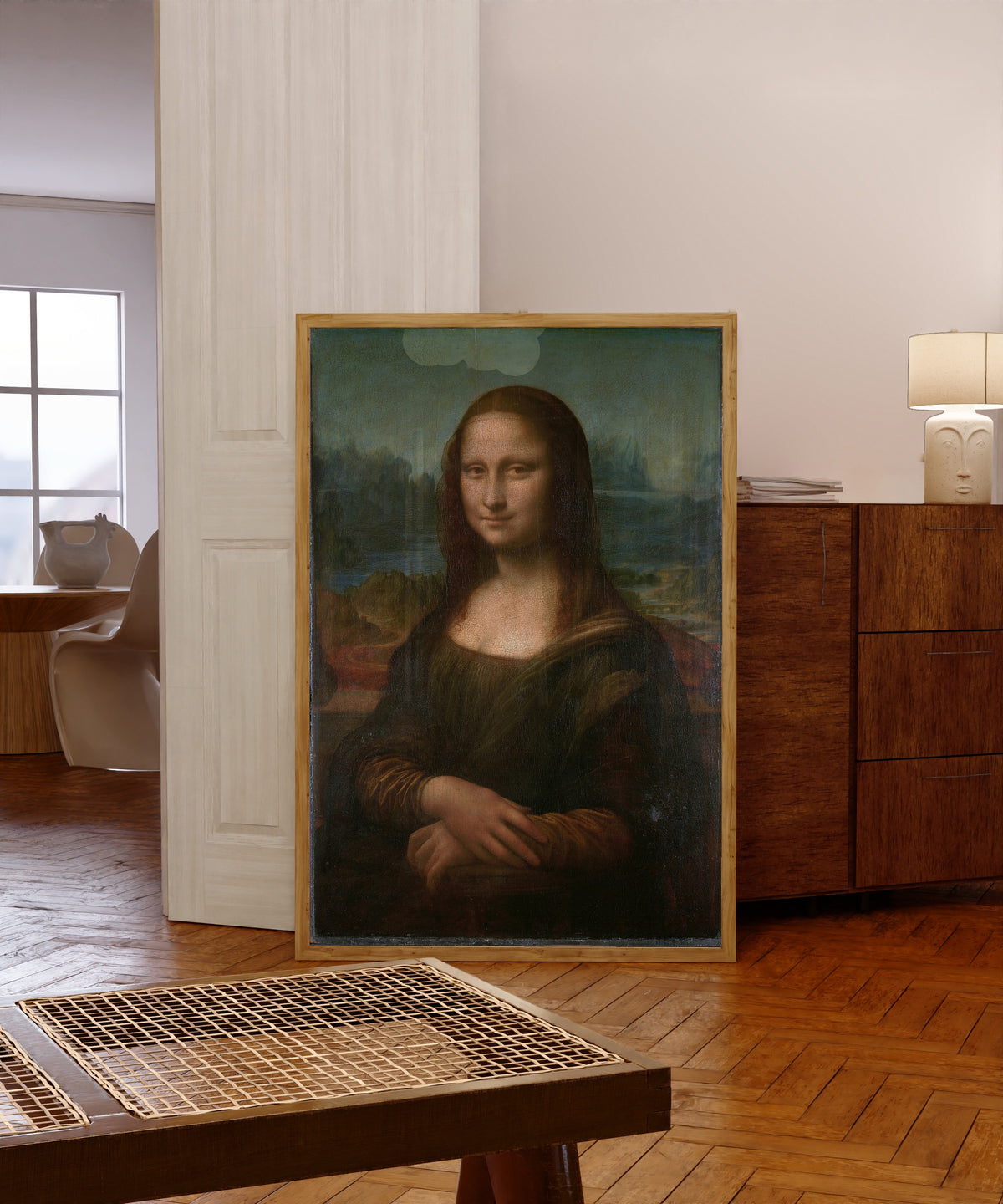 Framed art print of Mona Lisa by Leonardo da Vinci, in a light wood frame leaning in a warm room with a parquet floor