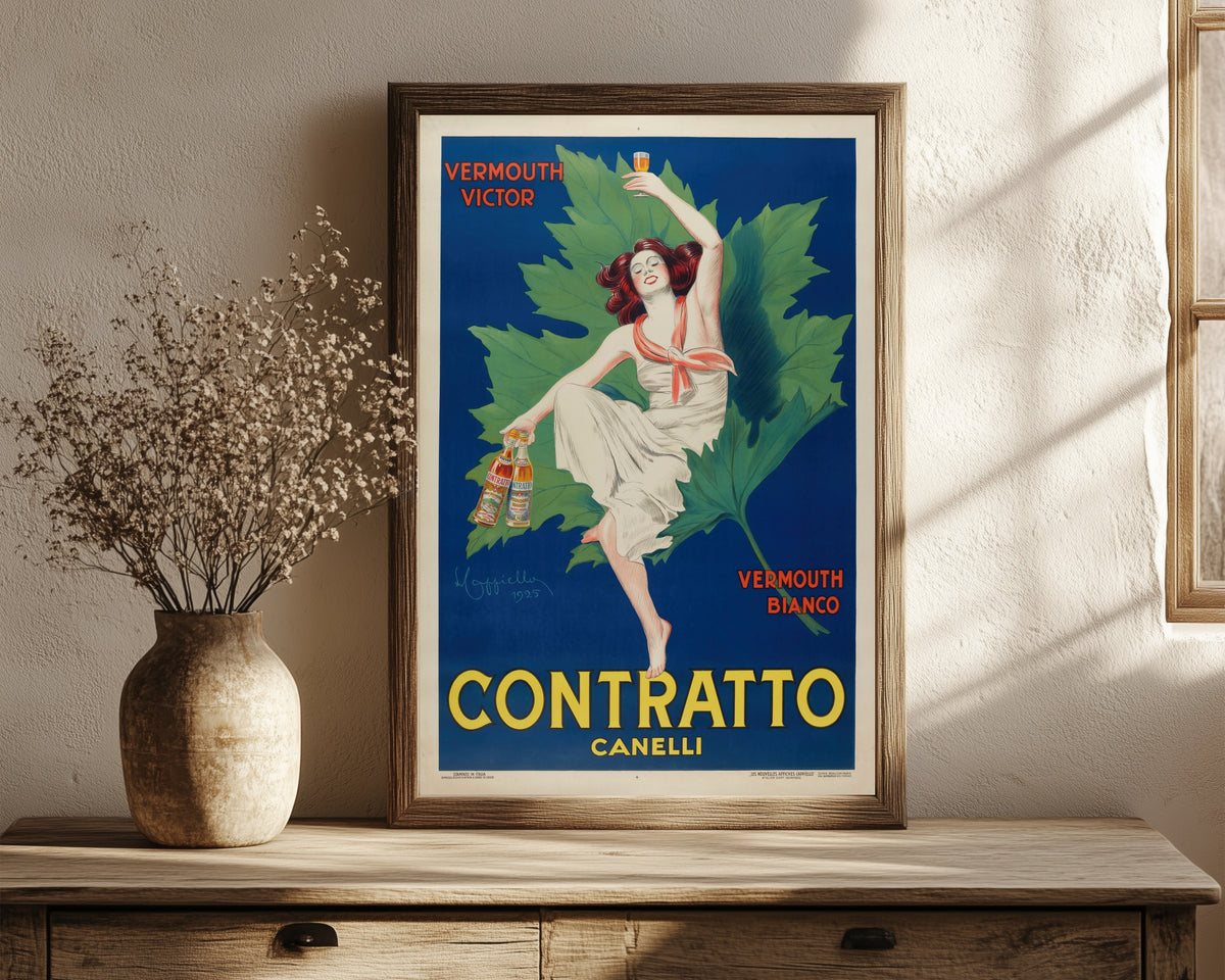 Framed art print of Contratto Canelli by Leonetto Cappiello, in a dark wood frame leaning on a rustic console beside dried flowers