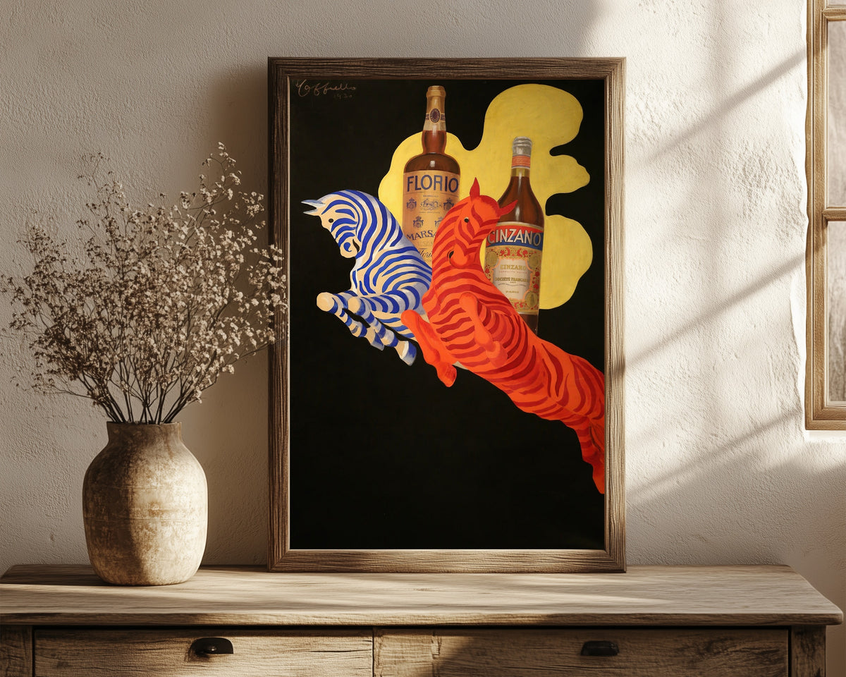 Framed art print of Florio Cinzano by Leonetto Cappiello, in a dark wood frame leaning on a rustic console beside dried flowers