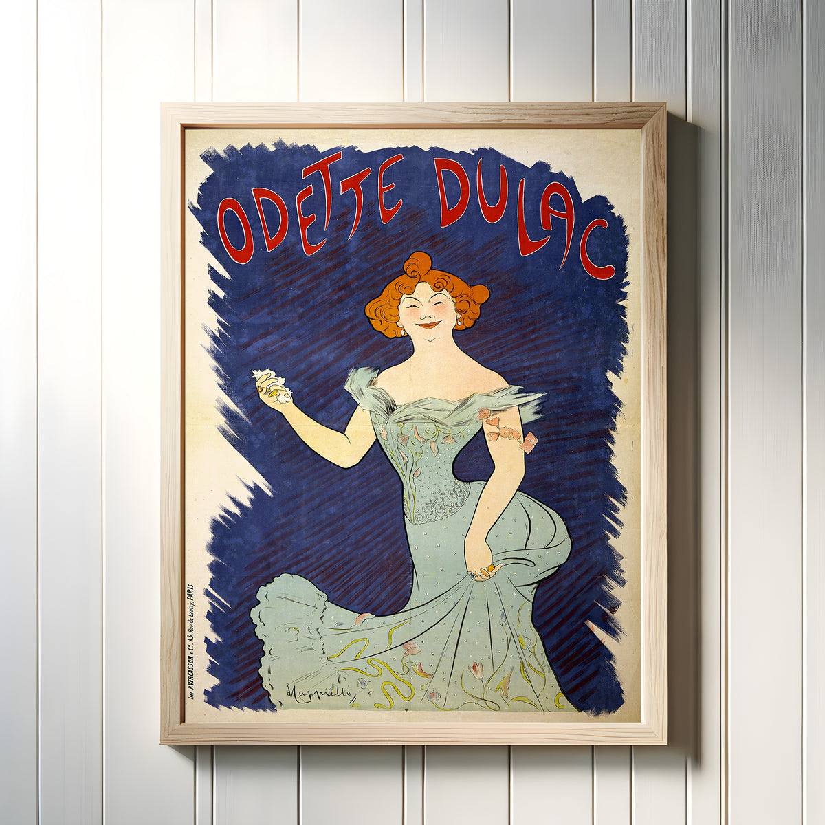 Framed art print of Odette Dulac by Leonetto Cappiello, in a light wood frame on a white panelled wall