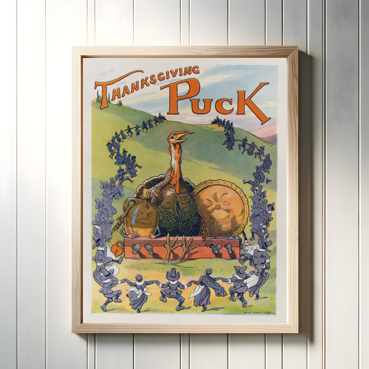 Framed art print of Thanksgiving Puck, 1913 by Louis Glackens, in a light wood frame on a white panelled wall