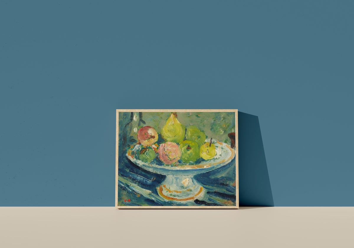 Framed art print of Le Compotier by Louis Valtat, in a light wood frame leaning on a blue wall