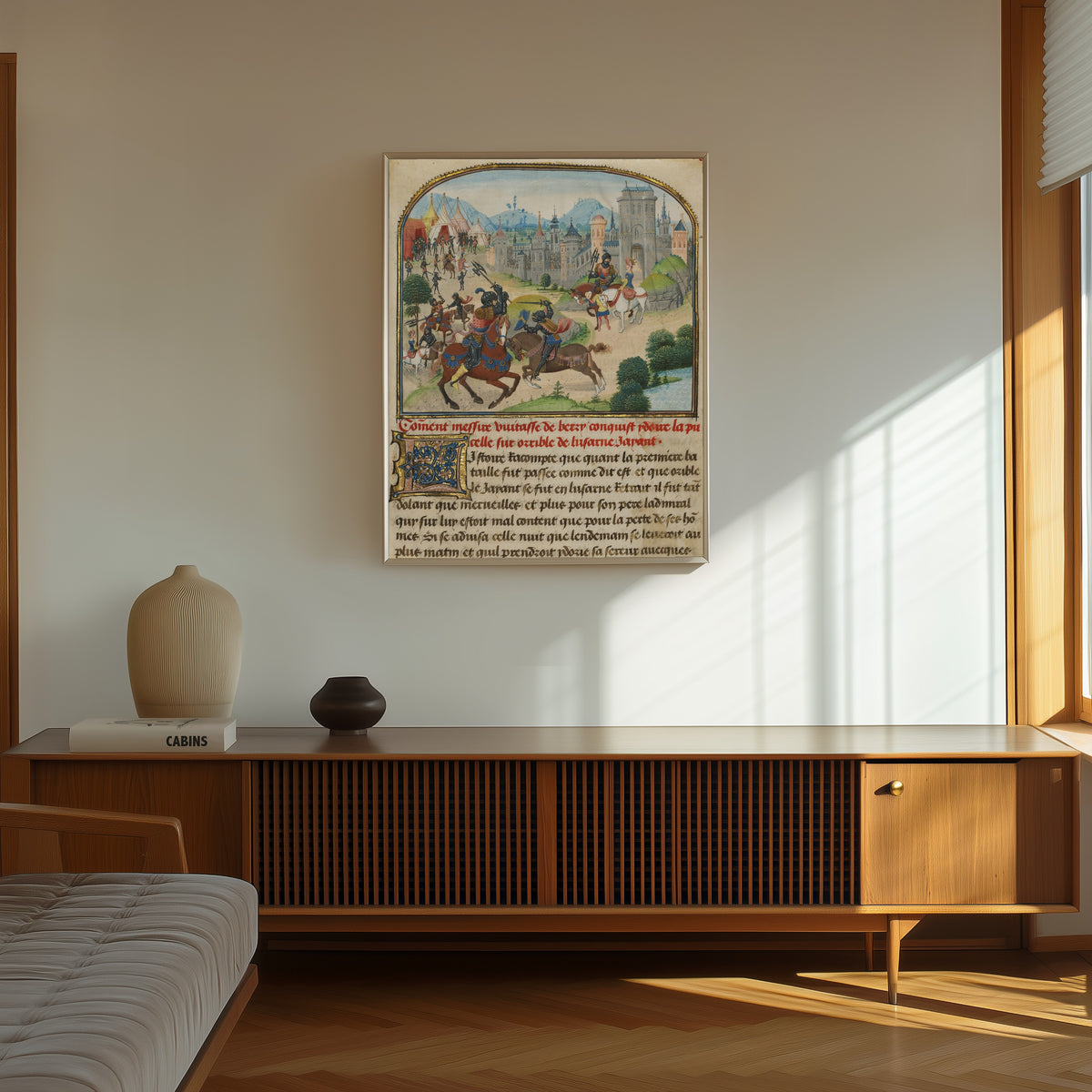 Framed art print of The Abduction of Ydoire by Loyset Liédet and Pol Fruit, in a thin light frame on a sunlit wall above a wooden sideboard
