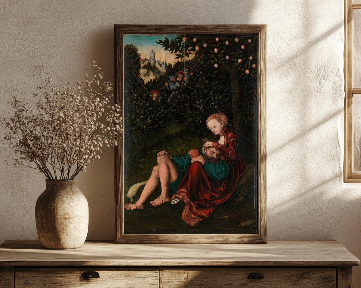 Framed art print of Samson and Delilah by Lucas Cranach the Elder, in a dark wood frame leaning on a rustic console beside dried flowers
