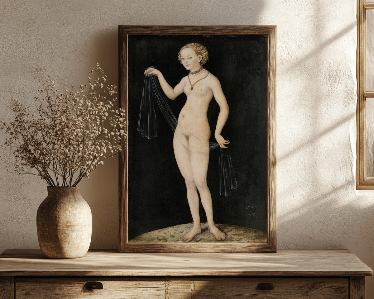 Framed art print of Venus by Lucas Cranach the Elder, in a dark wood frame leaning on a rustic console beside dried flowers