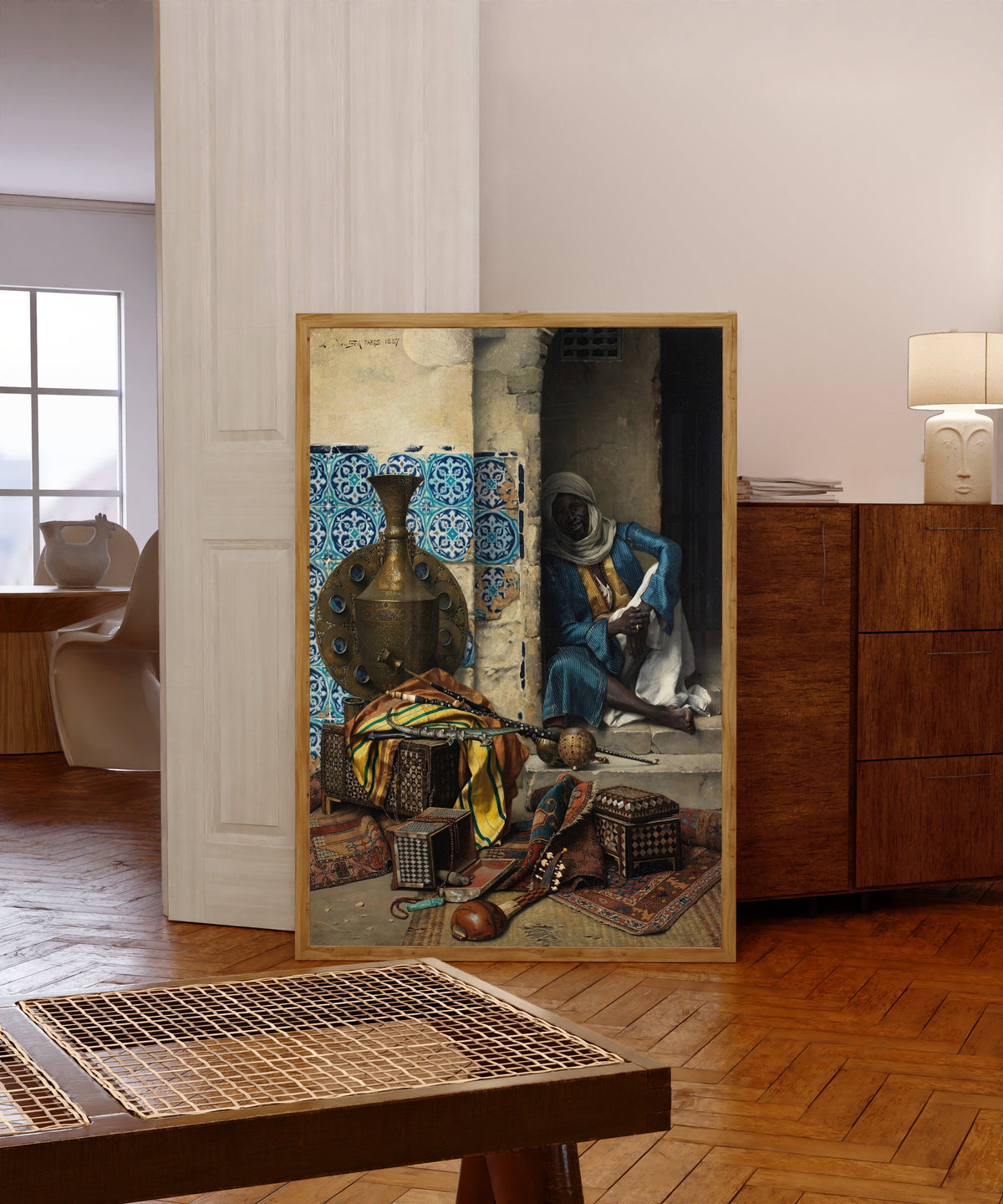 Framed art print of The Artefacts Dealer by Ludwig Deutsch, in a light wood frame leaning in a warm room with a parquet floor