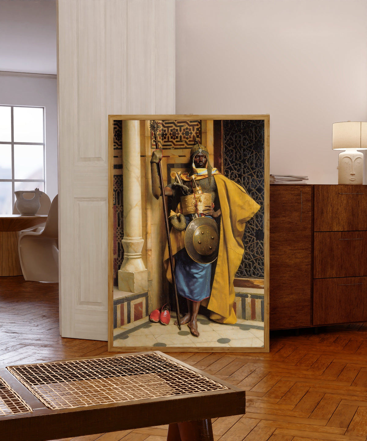 Framed art print of The Moorish Guard by Ludwig Deutsch, in a light wood frame leaning in a warm room with a parquet floor