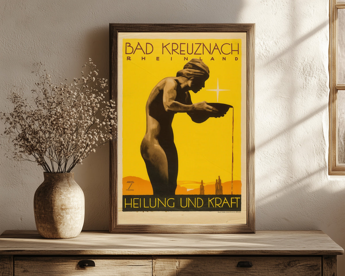 Framed art print of Bad Kreuznach by Ludwig Hohlwein, in a dark wood frame leaning on a rustic console beside dried flowers