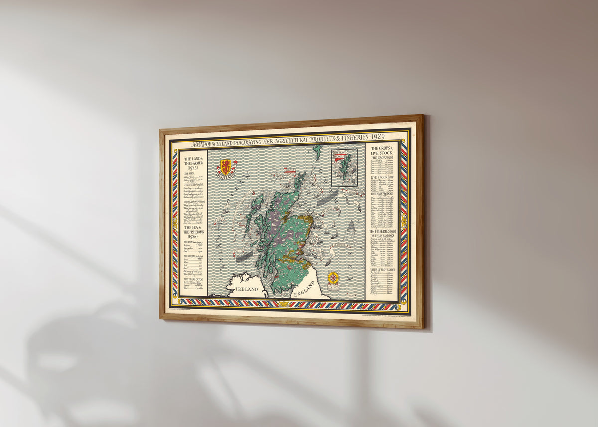 Framed art print of A Map of Scotland Portraying Her Agricultural… by MacDonald Gill, in a light wood frame on a sunlit white wall, seen at a slight angle