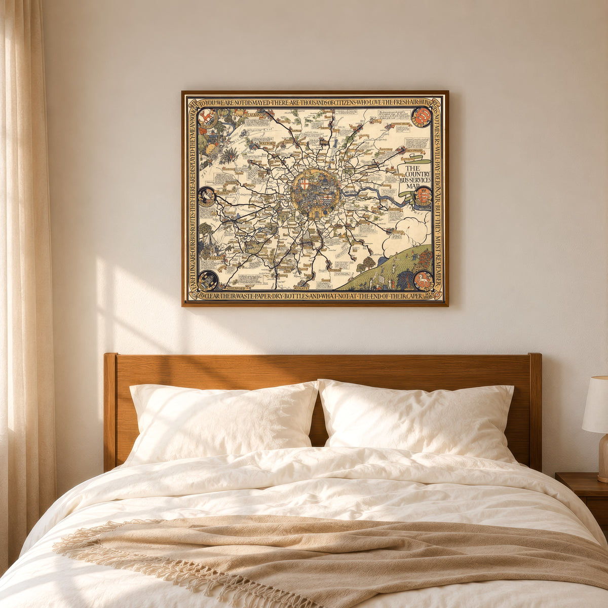 Framed art print of The Country Bus-Services Map, London and Vicinity by MacDonald Gill, in a slim wood frame above a bed in a sunlit bedroom