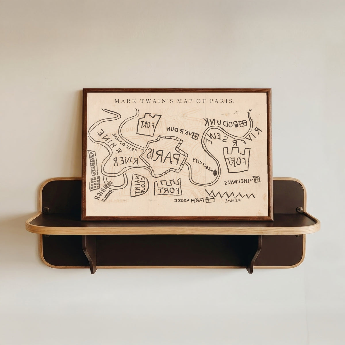 Framed art print of Mark Twain's Map of Paris by Mark Twain, in a dark wood frame resting on a wall shelf