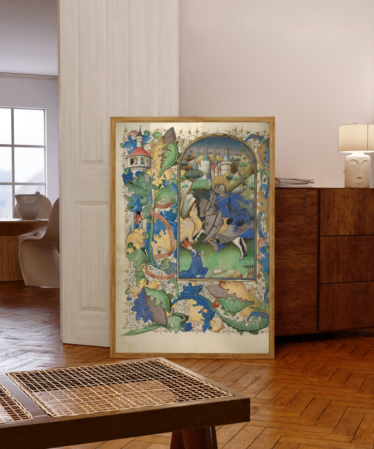 Framed art print of Saint George and the Dragon by Master of Guillebert de Mets, in a light wood frame leaning in a warm room with a parquet floor