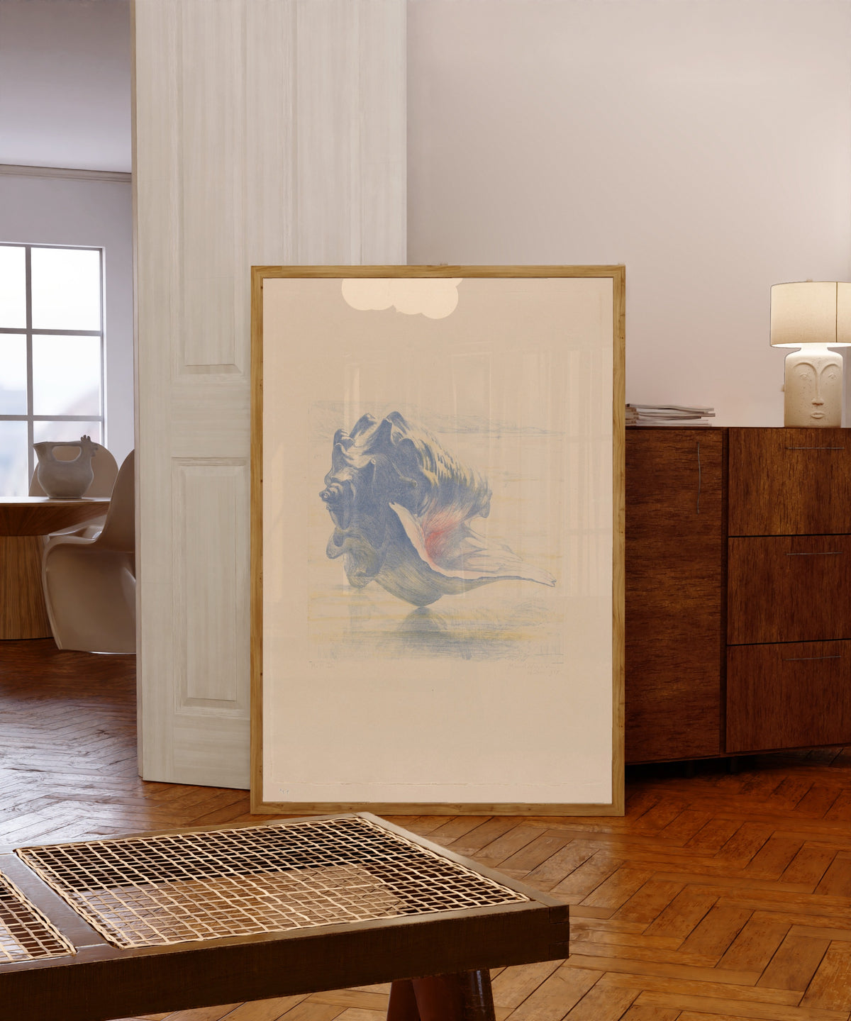 Framed art print of Seashells by Maurits van der Valk, in a light wood frame leaning in a warm room with a parquet floor