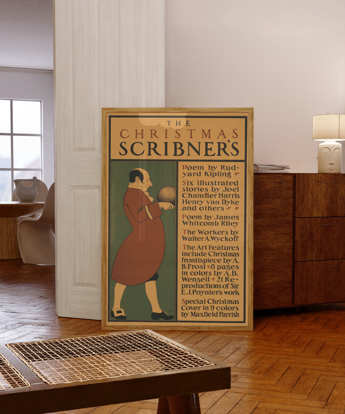 Framed art print of The Christmas Scribner’s by Maxfield Parrish, in a light wood frame leaning in a warm room with a parquet floor