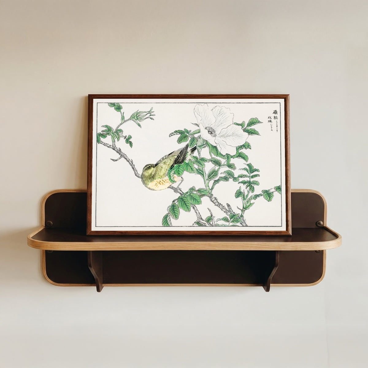 Framed art print of Brown-eared Bulbul and Rosa Rugosa by Numata Kashū, in a dark wood frame resting on a wall shelf