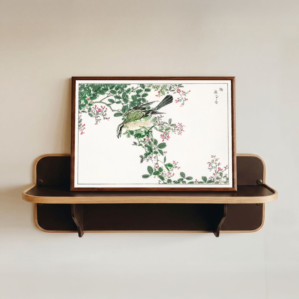 Framed art print of Bull-headed Shrike and Bush Clover by Numata Kashū, in a dark wood frame resting on a wall shelf