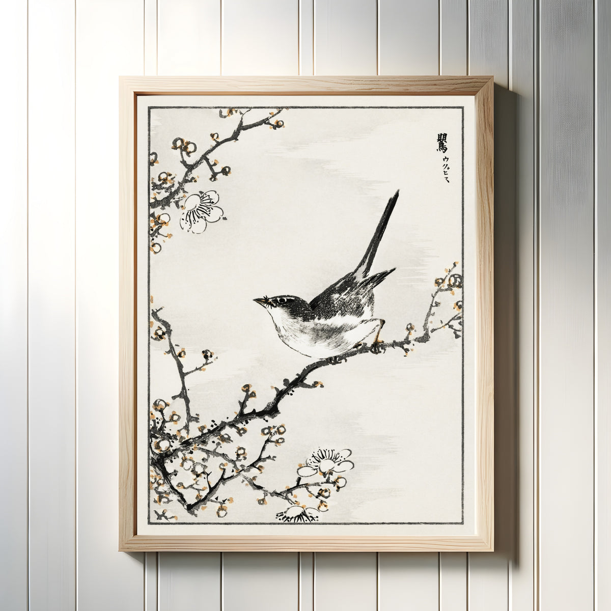 Framed art print of Bush-warbler and White Plum Tree by Numata Kashū, in a light wood frame on a white panelled wall