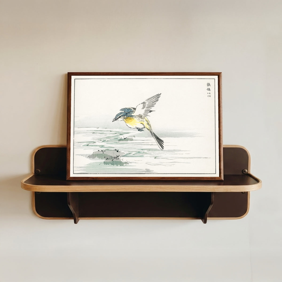 Framed art print of Wagtail over a Stream by Numata Kashū, in a dark wood frame resting on a wall shelf