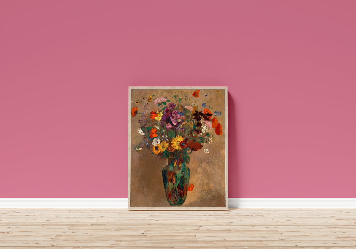 Framed art print of Large Bouquet of Wildflowers by Odilon Redon, in a light wood frame leaning on a pink wall above a wooden floor