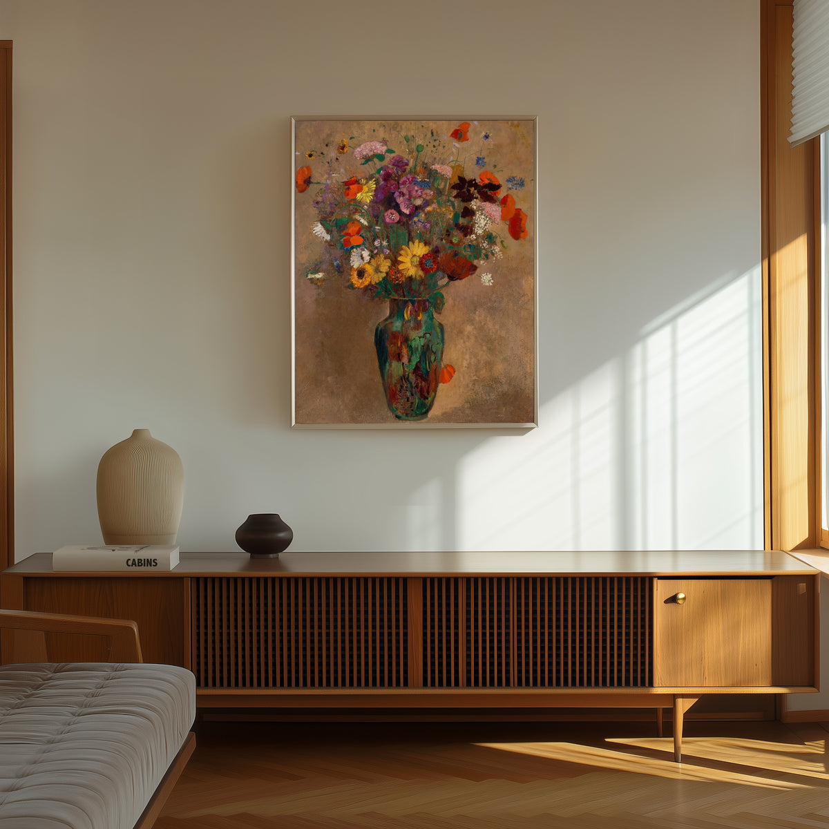 Framed art print of Large Bouquet of Wildflowers by Odilon Redon, in a thin light frame on a sunlit wall above a wooden sideboard