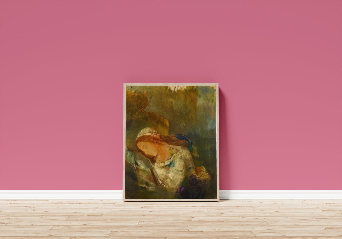 Framed art print of Ophelia (Striped Headscarf) by Odilon Redon, in a light wood frame leaning on a pink wall above a wooden floor