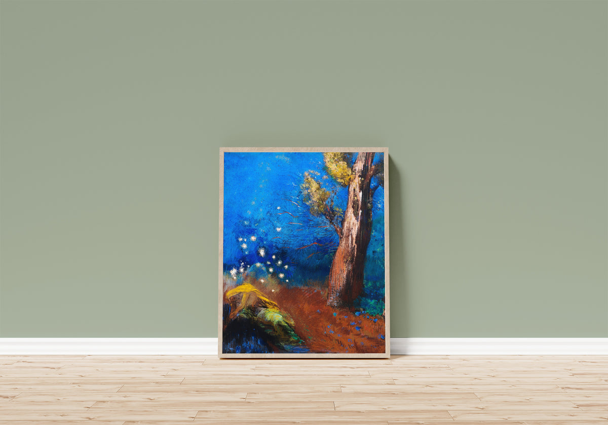Framed art print of The Death of Buddha by Odilon Redon, in a light wood frame leaning on a sage green wall above a wooden floor