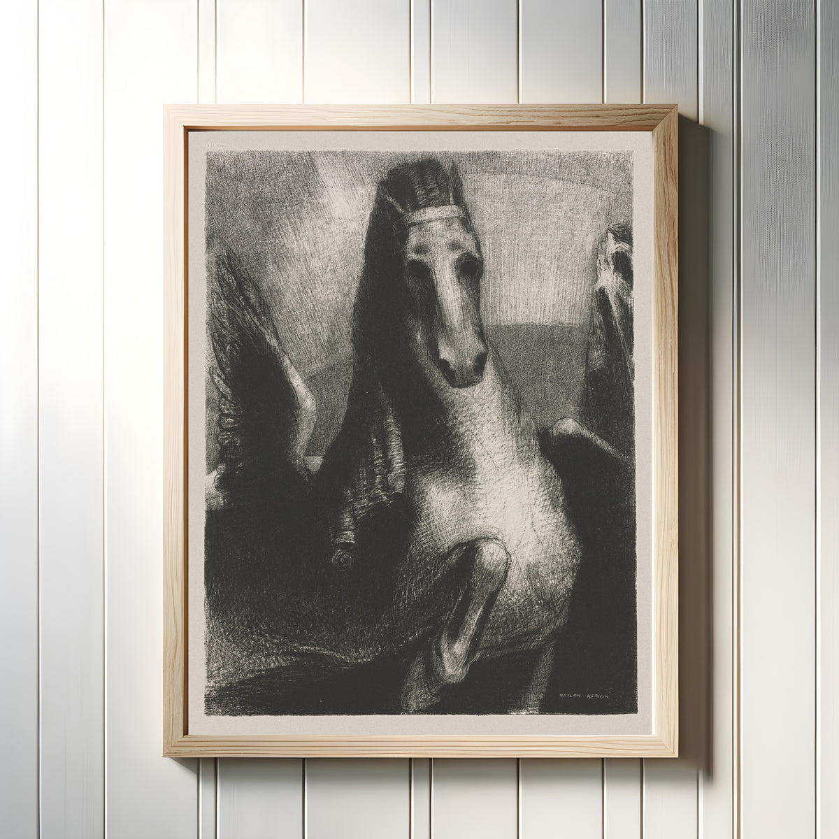 Framed art print of The Wing by Odilon Redon, in a light wood frame on a white panelled wall