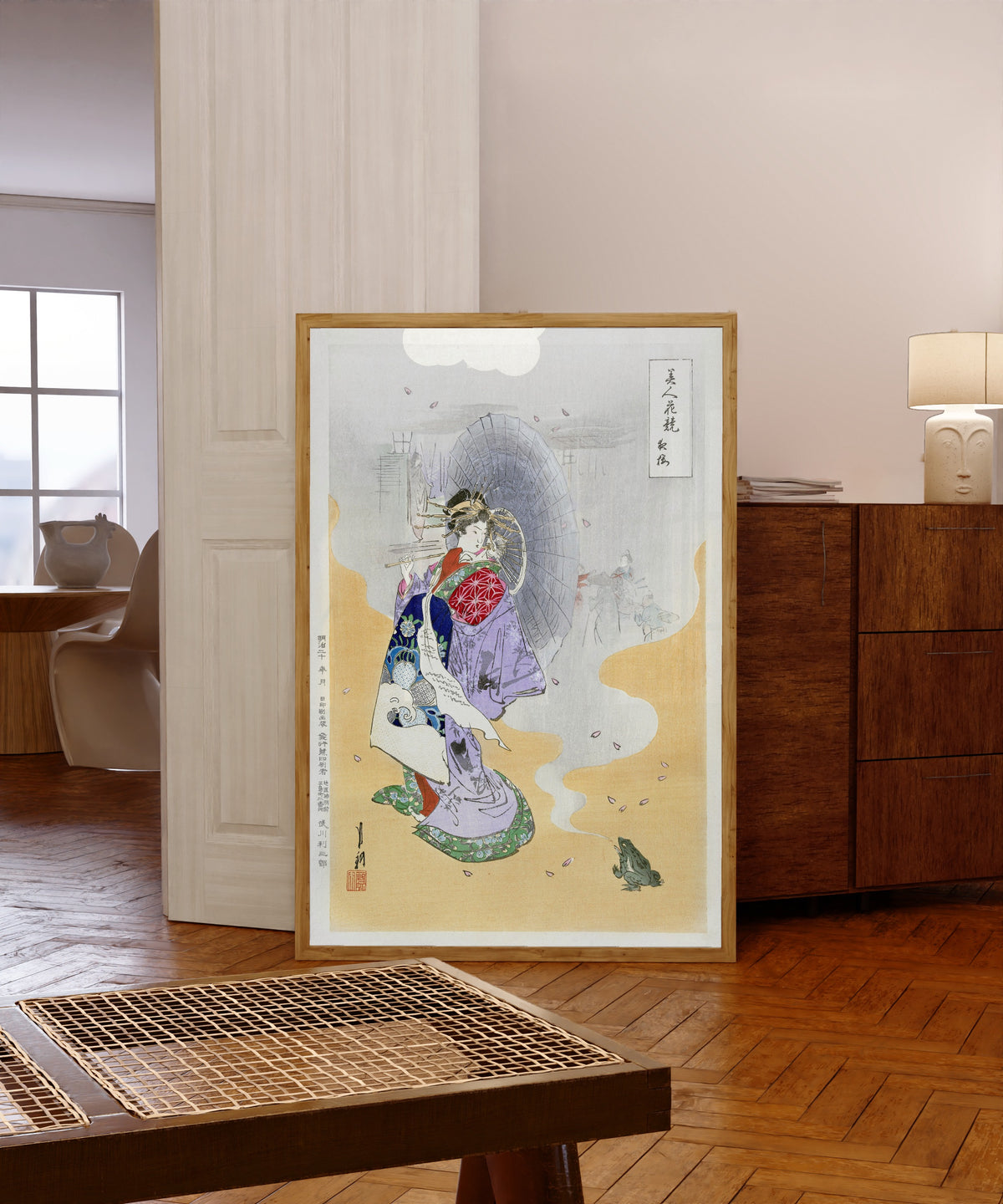Framed art print of Courtesan and Frog (1887–1896) by Ogata Gekkō, in a light wood frame leaning in a warm room with a parquet floor