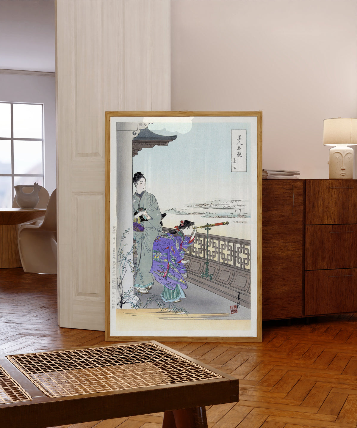 Framed art print of The Binoculars (1887–1896) by Ogata Gekkō, in a light wood frame leaning in a warm room with a parquet floor