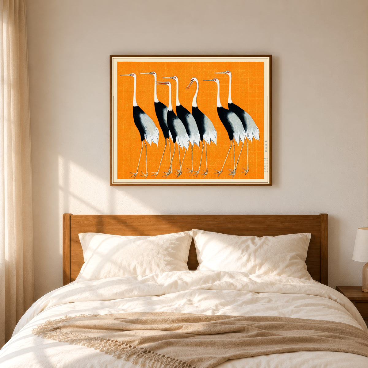 Framed art print of Cranes in Orange by Ogata Korin, in a slim wood frame above a bed in a sunlit bedroom